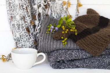 Atkı, süveter, şapka örgü yünü, hayat tarzının sıcak kahvesi kış mevsimi dekorasyonunda arka planda beyaz ahşap üzerine rahatla.