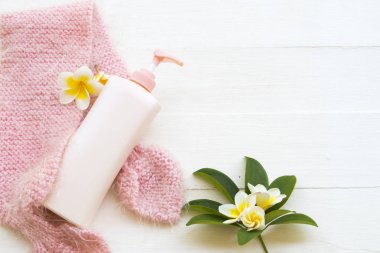Bitkisel kozmetik vücut losyonu vücut losyonu bakım ile örgü yün kadın eşarp kış mevsiminde rahatlayın ve çiçek franigpani düzenleme düz arka plan beyaz ahşap üzerine yatar