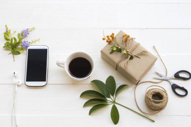 Festivalde özel bir gün için hediye kutusu Noel ve yeni yıl için sıcak kahve, cep telefonu yaşam tarzı düzenleme düz arka planda beyaz ahşap üzerinde yatıyordu