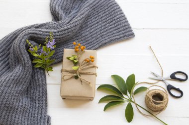 Noel 'de ve yılbaşında halat, makas, çiçek ve yaprak ile özel bir gün için hediye kutusu. Kış sezonu düzenleme tarzında yün örgü ören bir kadın. 