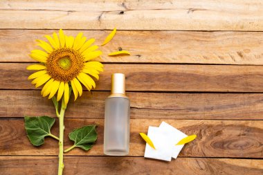 Terapi, pamuk doğal kozmetik içeren ilk serum tonerleri cilt için bitkisel sağlık hizmetleri sunar. Kadın yüzü güzelliği ve sarı çiçek ayçiçeği düzenleme arka plan tahtasının üzerinde düz bir şekilde yatar.