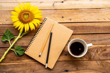 Sıcak kahve, sarı çiçekler, ayçiçeği düzenleme arka plan tahtasının üzerinde düz bir şekilde duran iş planlayıcısı.