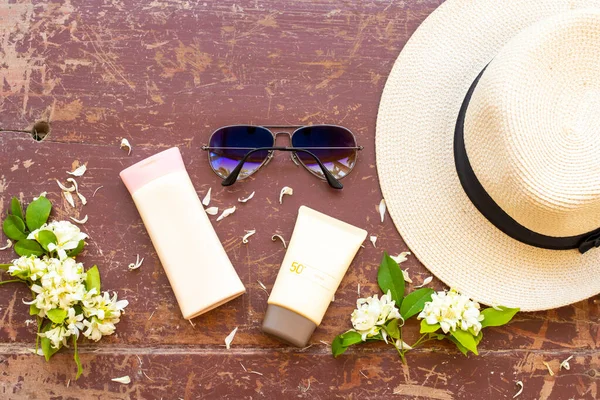 sunscreen spf50 ,body lotion cosmetics health care for skin  with sunglasses, hat ,white flowers jasmine of lifestyle woman relax in summer season arrangement flat lay style on background wooden