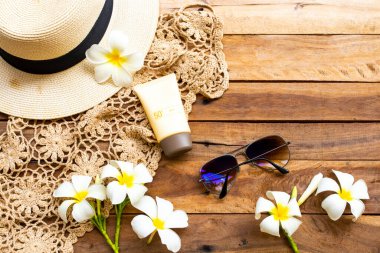 Güneş kremi spf50 cilt bakımı için tığ işi, çiçek, frangipani, güneş gözlüğü, kadın şapkası yaz düzeninde rahatla arka plan tahtasına düz bir şekilde uzan