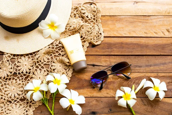 Güneş kremi spf50 cilt bakımı için tığ işi, çiçek, frangipani, güneş gözlüğü, kadın şapkası yaz düzeninde rahatla arka plan tahtasına düz bir şekilde uzan