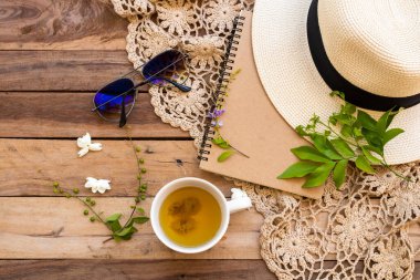 Sıcak kasımpatı çayı, beyaz çiçekler yasemin, şapka, güneş gözlüğü, örgü ören hayat tarzı kadınların iş planlayıcısı yaz aranjmanında düz bir şekilde tahtaya uzan.