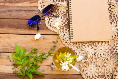 İş planlayıcısı soğuk içecekler kasımpatı, beyaz çiçekler yasemin, güneş gözlüğü, örgü ören hayat tarzı kadın. Yaz aranjmanında rahat ol, ahşap üzerine uzan.