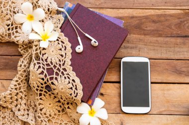 defter, cep telefonu, örgü ipliği ve beyaz çiçekler Frangipani yaşam tarzı gevşeme yaz düzenleme düz arka plan ahşap üzerinde yatıyordu 
