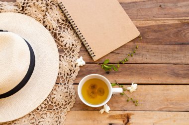 İş planlayıcısı sıcak kasımpatı çayı, beyaz çiçekler yasemin, şapka, örgü ören hayat tarzı kadın yaz aranjmanında rahatla tahta üzerine uzan