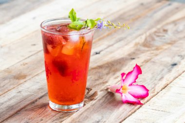 Bitkisel sağIıklı içecek soğuk çilek suyu. Arka plandaki ahşap süslemede pembe hayat çiçeği.