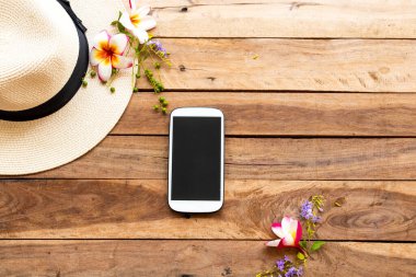 Cep telefonu, şapka ve hayat tarzının çiçekleri. Rahat ol. Arka plandaki tahta üzerine yaslan.