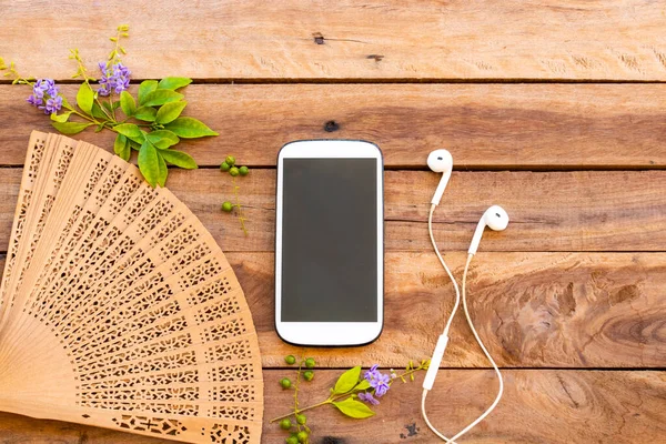 mobile phone ,earphone and wooden fan of lifestyle woman relax arrangement flat lay style on background wooden