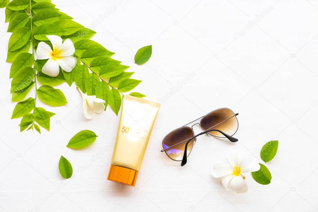 natural cosmetics sunscreen spf50 health care for skin face with flowers frangipani ,leaf of lifestyle woman relax in summer season arrangement flat lay style on background white wooden