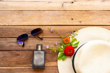 Parfüm, güneş gözlüğü ve hayat tarzı kadın. Yaz boyunca mor çiçeklerle rahatla. Zinnia düzenleme tarzı arka planda, ahşap üzerine uzan.