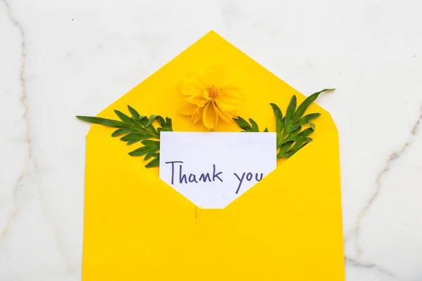 封筒に手書きのメッセージカードと黄色い花のコスモス配置平置きはがき風で背景は白 — ストック写真