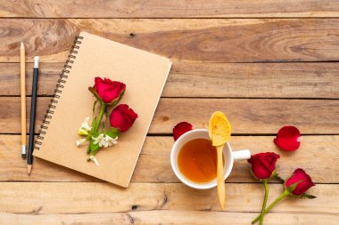 İş planlayıcısı bitkisel sağlıklı içecekler limon çayı, kırmızı gül çiçekleri düzenleme düz arka plan ahşap üzerine yatar