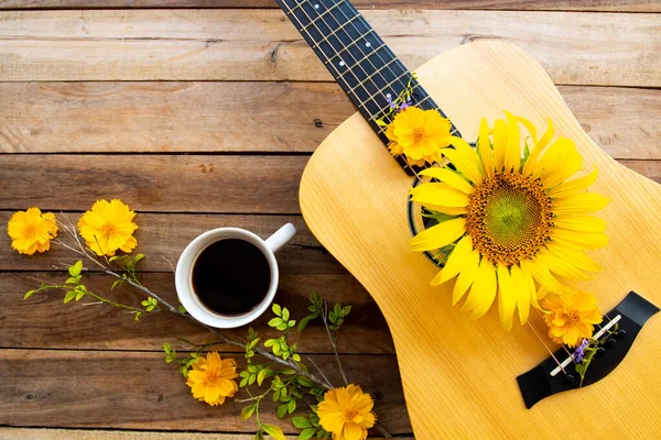 yellow flowers cosmos, sunflowers arrangement on acoustic guitar and hot coffee espresso decoration flat lay postcard style on background wooden
