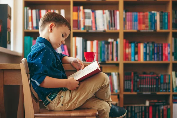 Reading boy with cup of tea — Stock Photo, Image