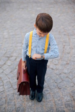 Boy verifying time on his silver watch on his hand clipart