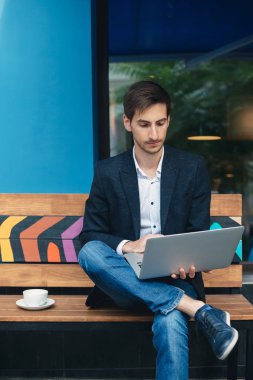 Dizüstü bilgisayarda çalışırken oturan genç adam