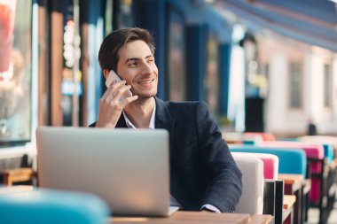 Genç girişimci dizüstü bilgisayar ve telefon üzerinde çalışıyor