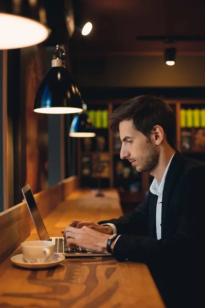 El hombre serio que trabaja en el ordenador portátil tomando café — Foto de Stock