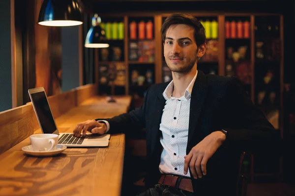 Sonriente hombre trabajando en portátil ang mirando a la cámara — Foto de Stock