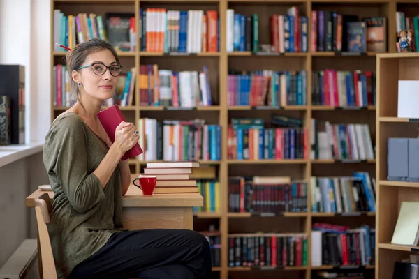 Fiatal gyönyörű nő tartani egy könyvet ő kezét mosolyogva — Stock Fotó