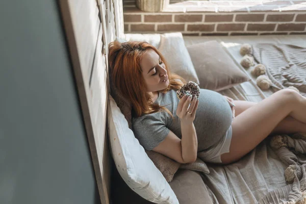 Těhotná žena jíst chutné koblihy — Stock fotografie