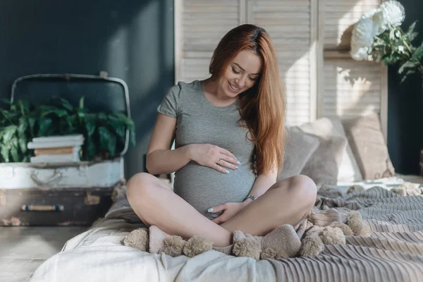 Těhotná žena dotýká a při pohledu na její břicho — Stock fotografie