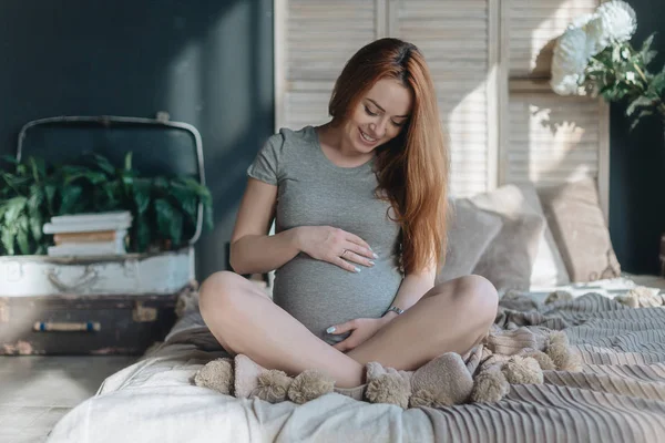 Donna incinta toccante e guardando al suo ventre — Foto Stock