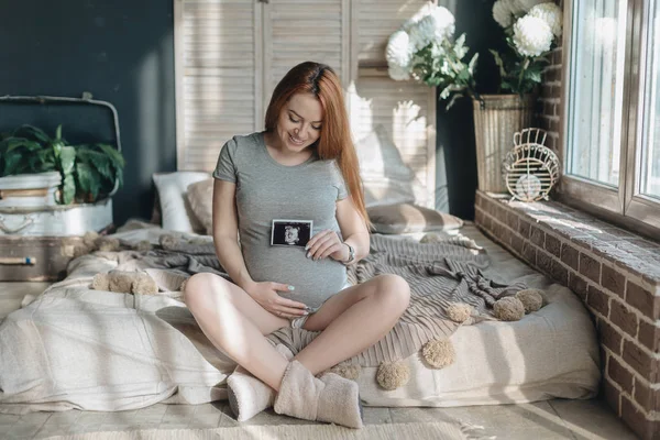 Těhotná žena drží ultrazvukové vyšetření dítěte — Stock fotografie