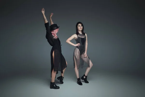 Две модные девушки в черных модных нарядах позируют — стоковое фото