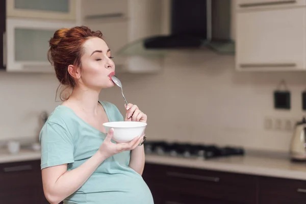 Vacker gravid kvinna äta spannmål — Stockfoto