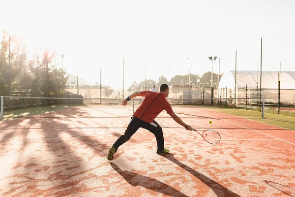 Młody człowiek jest grać w tenisa na świeże słoneczny poranek — Zdjęcie stockowe