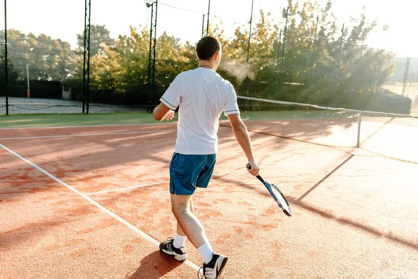 Człowiek, grać w tenisa w godzinach porannych w słońcu — Zdjęcie stockowe
