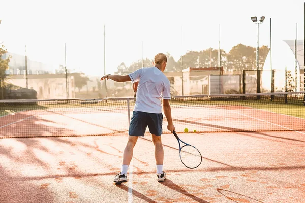 Man playing tennis in the morning in sunlight