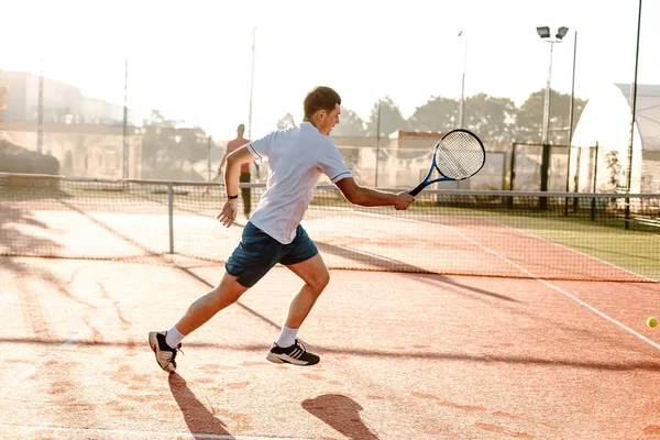 Hombre jugando tenis en la mañana en la luz del sol corriendo — Foto de Stock