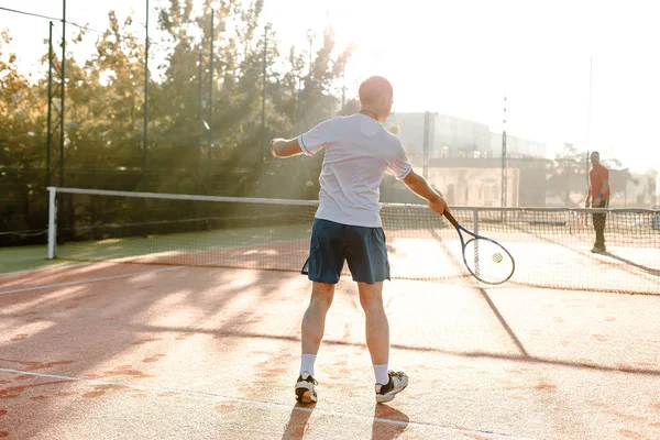 Hombre jugando al tenis en la mañana a la luz del sol — Foto de Stock
