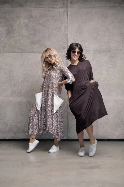 Duas jovens mulheres alegres e na moda usando óculos de sol — Fotografia de Stock