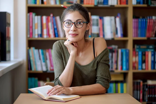 Giovane bella donna con un libro in una libreria — Foto Stock