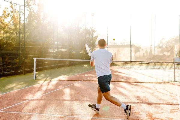 Hombre jugando al tenis en la mañana a la luz del sol — Foto de Stock