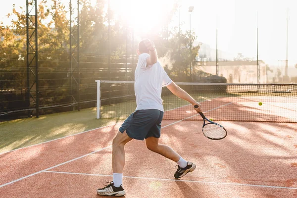 Hombre jugando al tenis en la mañana a la luz del sol — Foto de Stock