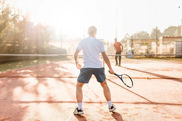 Człowiek, grać w tenisa w godzinach porannych w słońcu — Zdjęcie stockowe