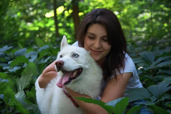 Mujer joven abrazando y golpeando a su perro — Foto de Stock