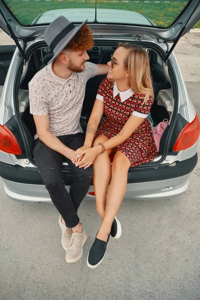 Pareja feliz pasar un buen rato juntos mientras se sienta en el maletero del coche —  Fotos de Stock