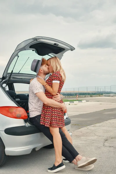 Joven hombre y mujer besando en el maletero del coche —  Fotos de Stock