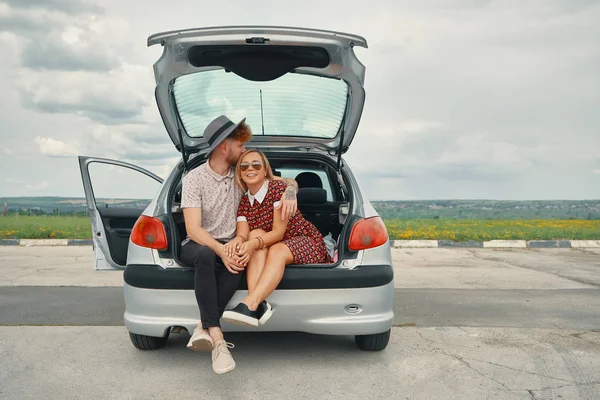 Ευτυχισμένο ζευγάρι έχουν καλή στιγμή μαζί ενώ κάθεται στο πορτ-μπαγκάζ αυτοκινήτου — Φωτογραφία Αρχείου