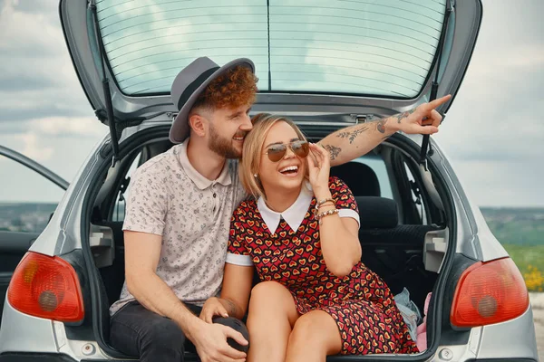 Pareja feliz pasar un buen rato juntos mientras se sienta en el maletero del coche —  Fotos de Stock