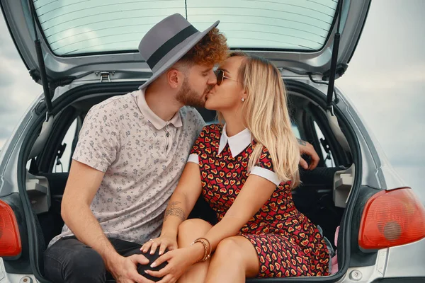 Joven hombre y mujer besando en el maletero del coche —  Fotos de Stock